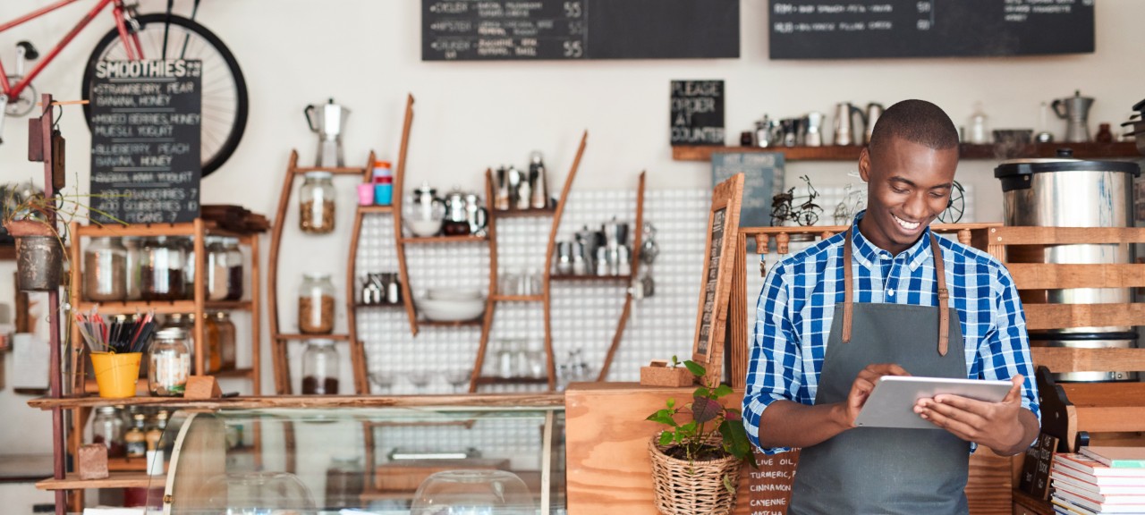 Photo of a smiling café owner holding a tablet