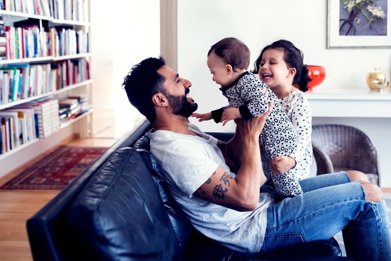 Dad playing with kids in a book-lined lounge