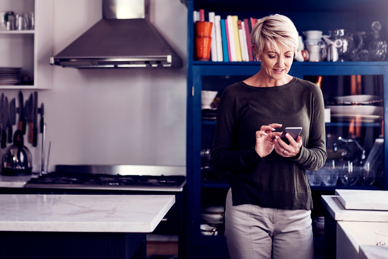 Woman using smartphone in kitchen