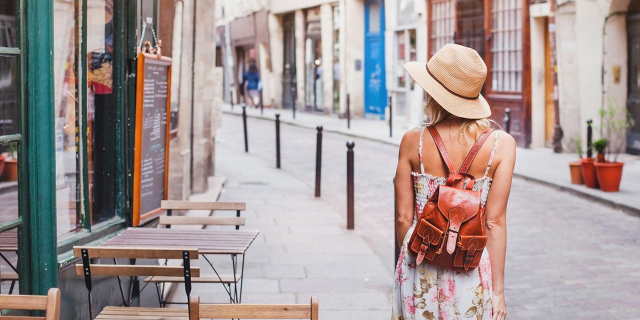 Image of a woman in a hat walking down a street in a European city