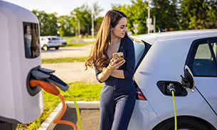 Car parked on a street and plugged into an electric charging station.