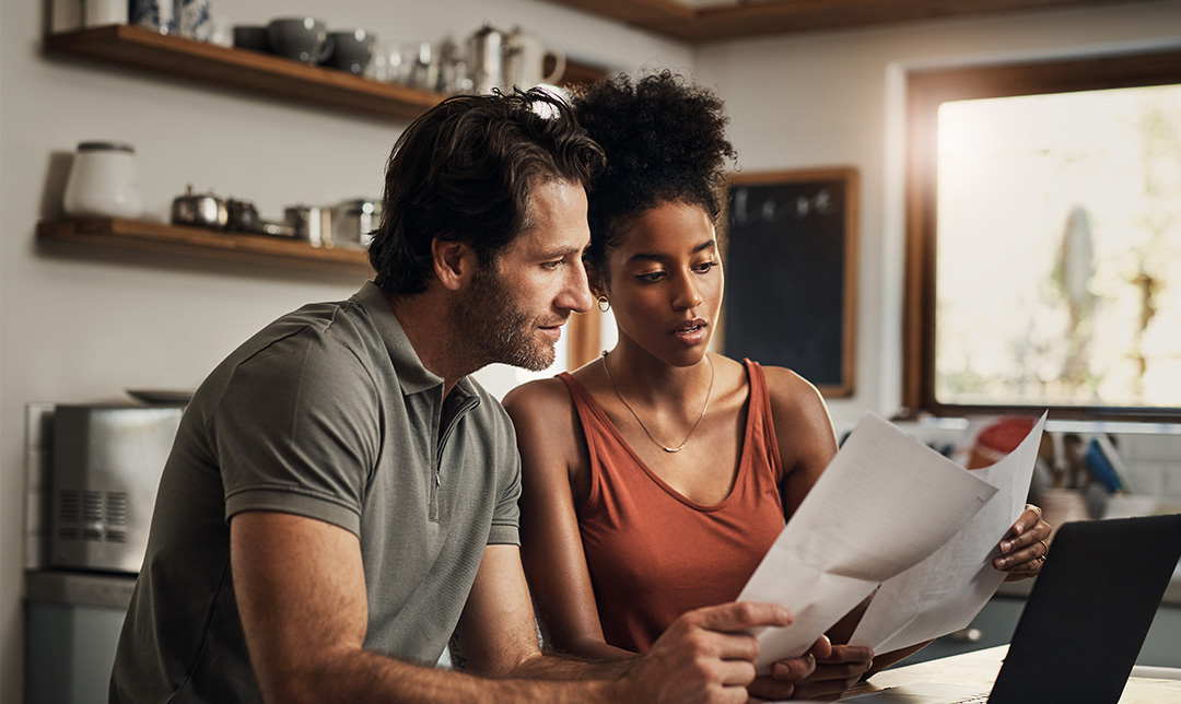 Couple looking at documents at laptop