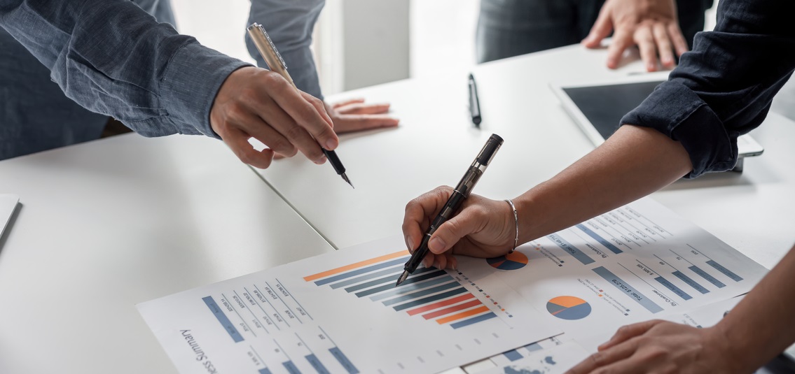 A couple of office workers reviewing a data sheet with graphs and charts